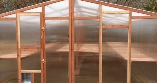 Backyard greenhouse kit with redwood framing and polycarbonate siding.