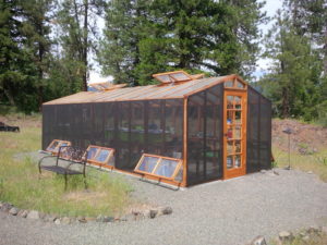Backyard DIY greenhouse kit with a redwood frame, polycarbonate paneling and shade cloth.