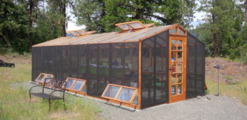 Backyard DIY greenhouse kit with a redwood frame, polycarbonate paneling and shade cloth.