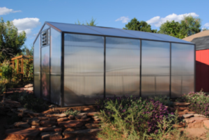 Backyard greenhouse kit with polycarbonate paneling and aluminum frame.